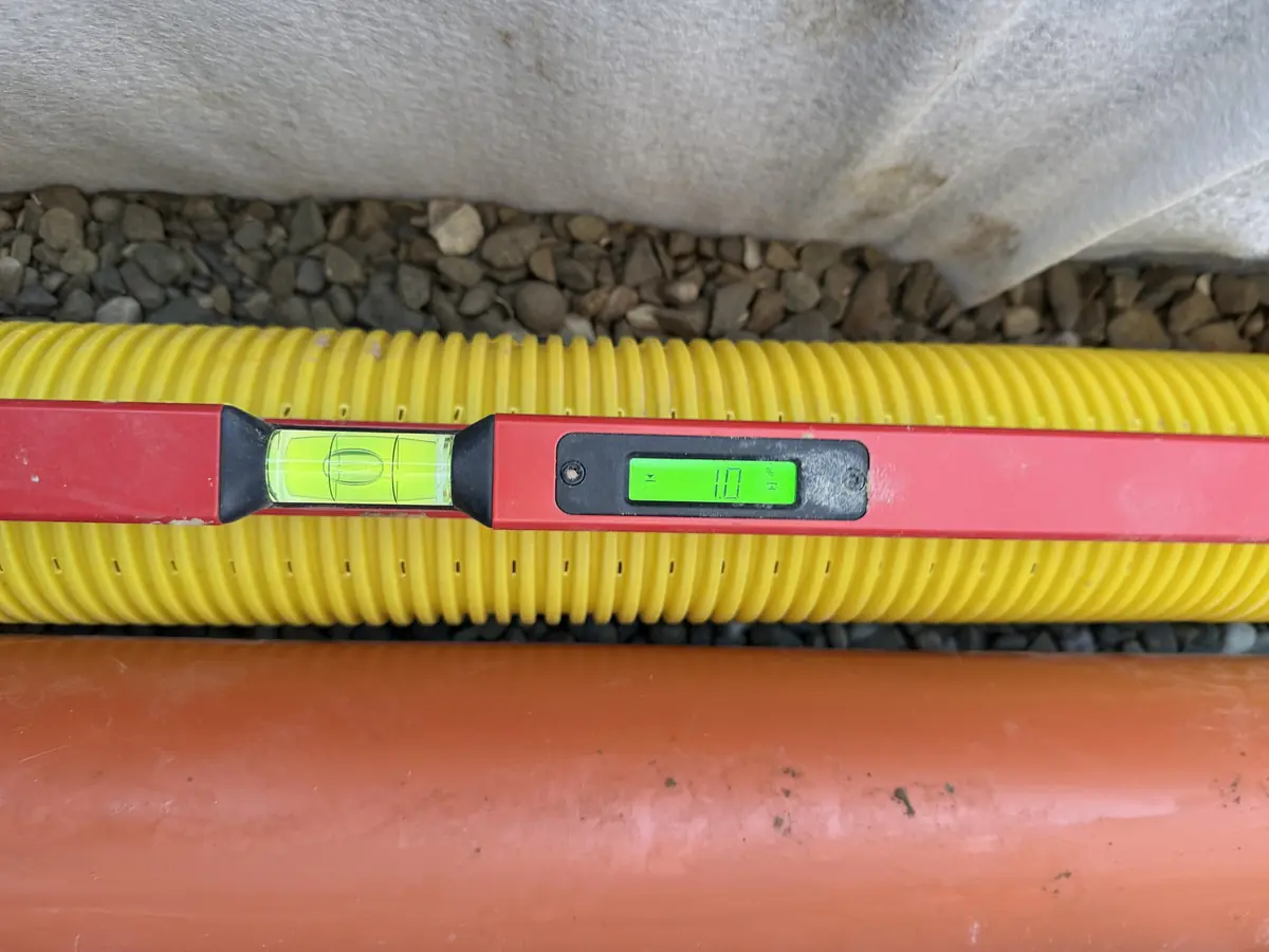 Kontrola spadku rury drenażowej poziomicą elektroniczną – odczyt 1,0% – RentBud