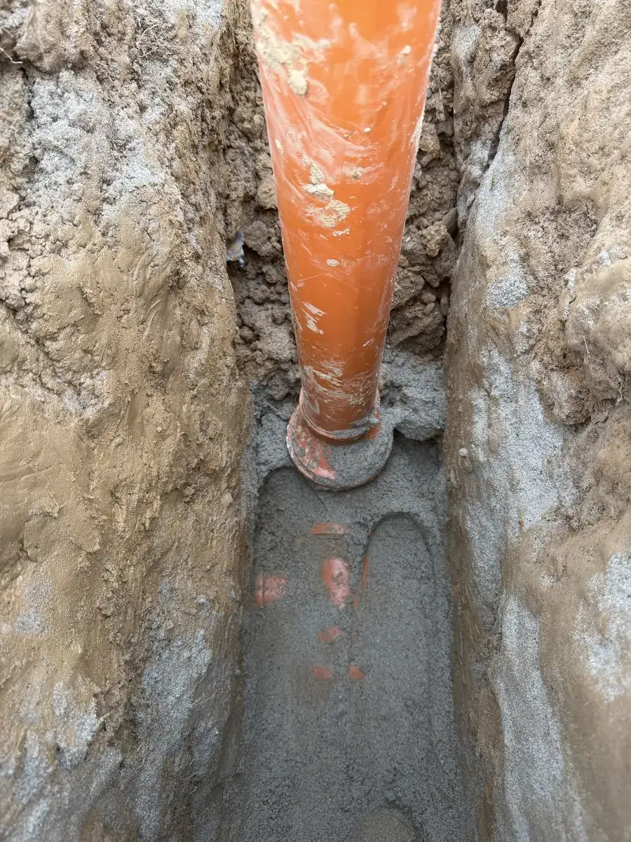Rury instalacji deszczowej w obsypce piaskowej na dnie wykopu
